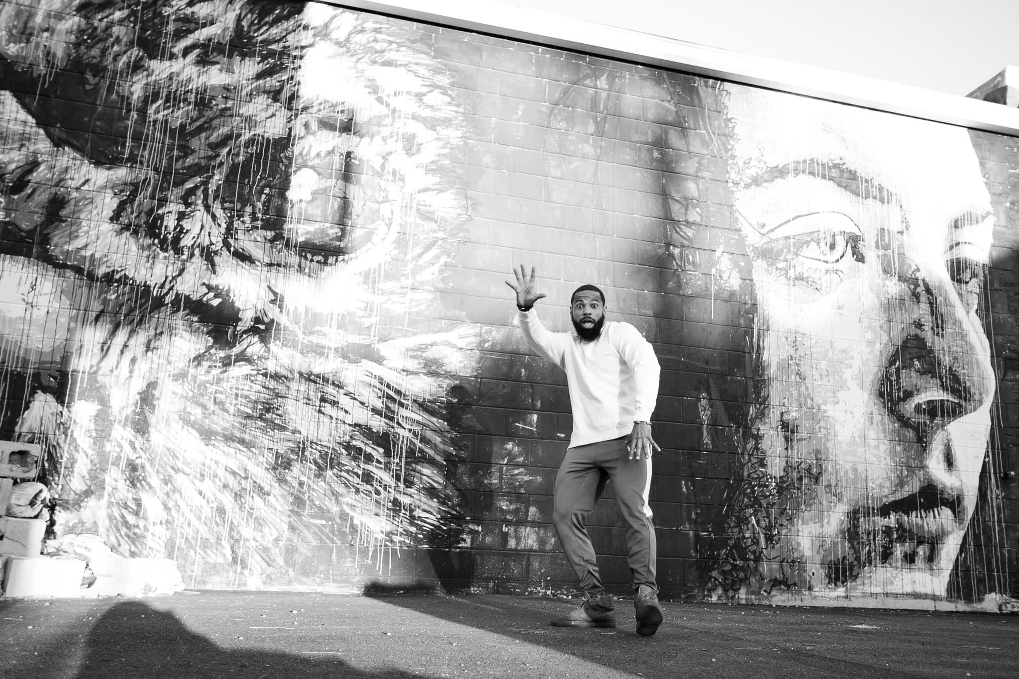 Black and white photo of Chris Frazier gesturing in front of a large mural
